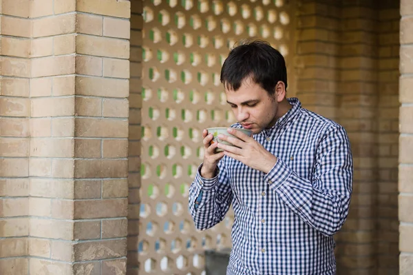 Retrato del joven feliz hombre sonriente bebiendo agua de manantial de la taza, al aire libre — Foto de Stock