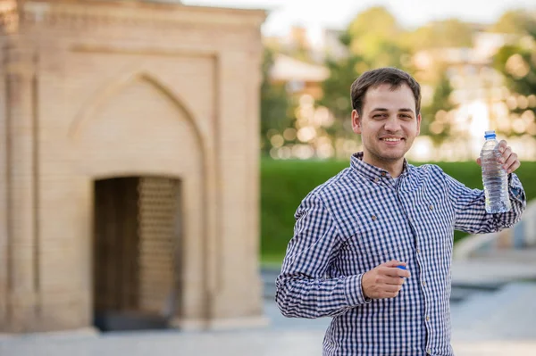 Knappe man drinken bronwater uit de fles in een park — Stockfoto