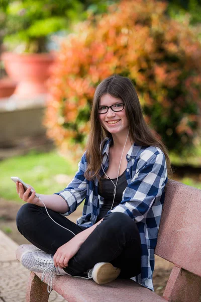 Moderna tonåring flicka med smart telefon i en park över grön bakgrund — Stockfoto