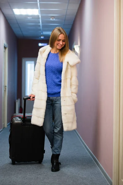 Mujer adulta positiva de pie en la sala con el equipaje embalado —  Fotos de Stock
