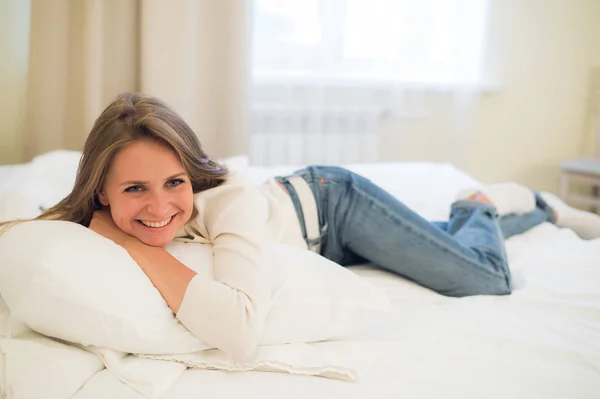 Sonriente mujer bonita pensativa acostada en la cama en casa — Foto de Stock