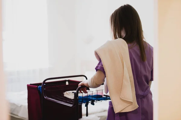 Junges Hausmädchen schiebt Karren beim Putzen von Hotelzimmern — Stockfoto