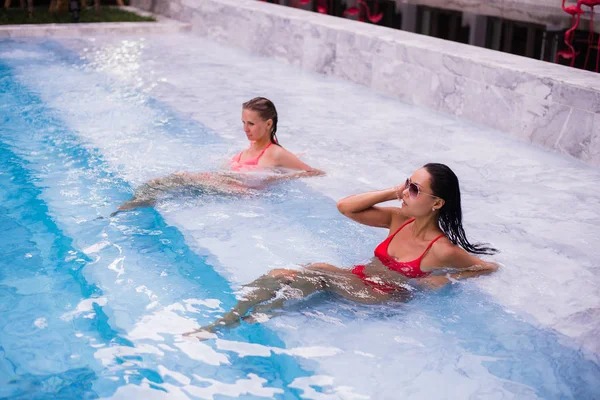 Mujeres jóvenes relajándose junto a la piscina —  Fotos de Stock