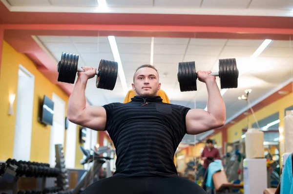 El atlético sostiene la barra sobre la cabeza en el gimnasio — Foto de Stock