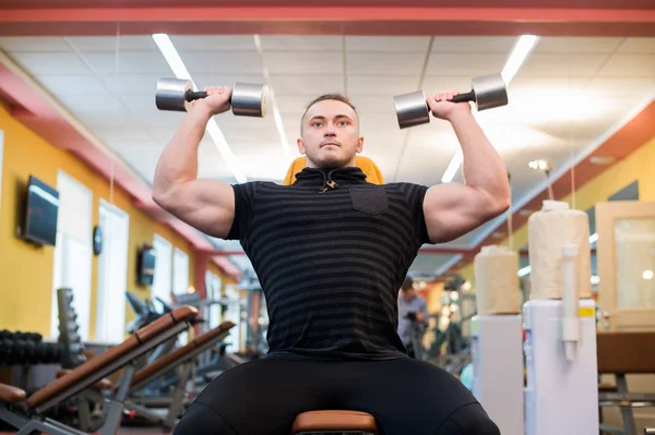 El atlético sostiene la barra sobre la cabeza en el gimnasio — Foto de Stock