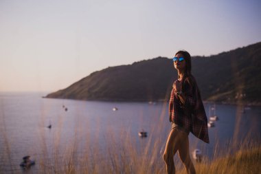 Bir kız deniz kenarında uçurumun kenarında duruyor veya okyanus ve sun valley adlı arıyorum. Bir gün batımı veya gündoğumu dağın tepesinden kadının. Gezgin kızı görüyor güneş doğarken