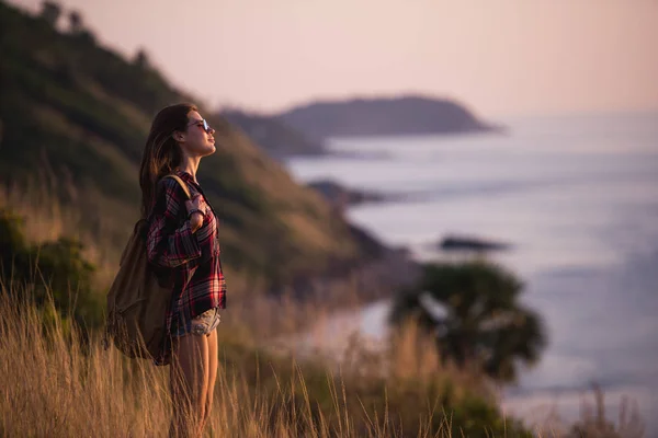 Sommer sonnige Lifestylemode Porträt einer jungen stylischen Hipsterfrau, die in den Bergen wandert, niedliches trendiges Outfit trägt, die Wochenenden lächelnd genießt, mit dem Rucksack reist. atemberaubender Meerblick auf einem — Stockfoto