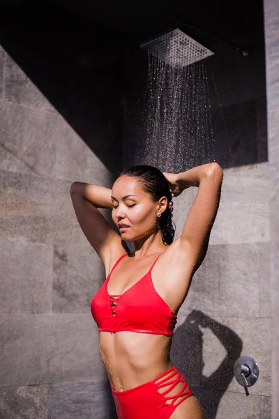 Una giovane donna sexy con un costume da bagno rosso che si fa la doccia all'esterno dell'hotel di lusso — Foto Stock