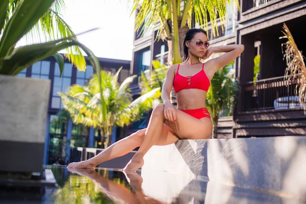 Bella donna sottile sexy che indossa bikini rosso rilassarsi vicino alla piscina all'aperto in resort — Foto Stock