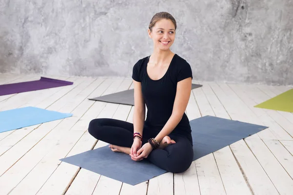 Siyah t-shirt, pantolon, meditasyon yoga sınıf katında oturumunda çalışma dışarı, pratik yoga, Ardha Padmasana egzersiz, yarım Lotus poz, oturan genç çekici kadın giyiyor