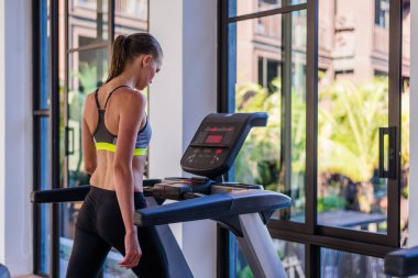 Yatay atış kadının sağlık spor kulübü lüks Resort, koşu bandı koşu. Yaz aylarında hotel adlı spa tesisinde büyük yaz manzaralı bir koşu bandı üzerinde çalışan bir spor salonunda egzersiz erkek 