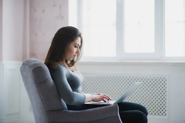 Ładna pani pracy na jej laptopie siedząc na fotelu — Zdjęcie stockowe