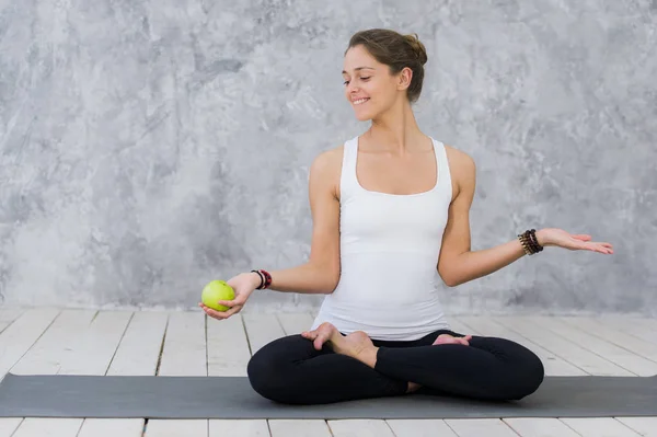 Caucasian beautiful healthy athletic sportive girl eat green apple after the training and looking at camera — Stock Photo, Image