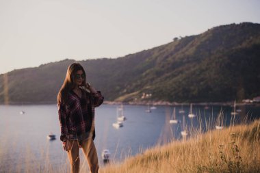 Hipster şık kadın seyahat etmek üstünde a deniz ya da okyanus batımını