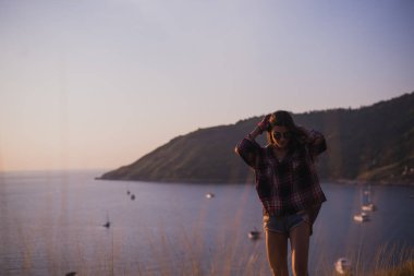 Bir kız deniz kenarında uçurumun kenarında duruyor veya okyanus ve sun valley adlı arıyorum. Bir gün batımı veya gündoğumu dağın tepesinden kadının. Gezgin kızı görüyor güneş doğarken