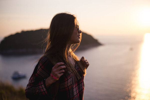 Young stylish hipster girl enjoy sunset on viewpoint. Travel woman with backpack