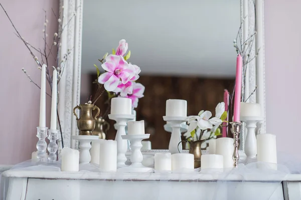 Design intérieur de chambre blanche avec de belles fleurs sur la table de service. Grand miroir classique créatif en arrière-plan . — Photo