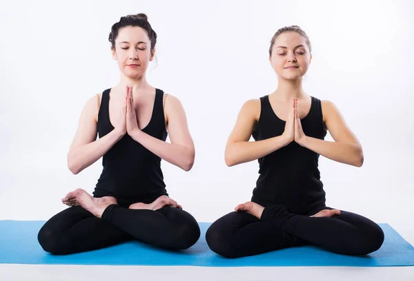 Ung man och kvinna gör yoga och meditera i lotusställning isolerad på vit bakgrund. — Stockfoto