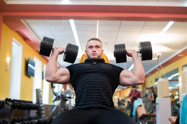 Sportos férfi, aki a súlyzó a fejét az edzőteremben — Stock Fotó