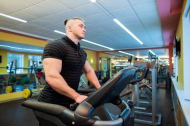 Spor salonunda bir koşu bandı üzerinde çalışırken çekici genç kaslı adam