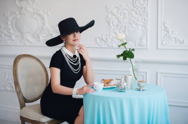 Ünlü oyuncu, çay içme ve yemek yeme kruvasan gibi şapkalı kadın.