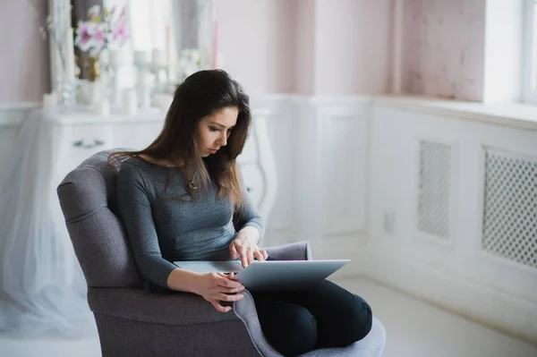 Mujer joven con portátil sentado en el sillón en casa — Foto de Stock