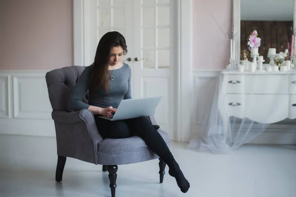 Όμορφη κυρία που εργάζονται για το laptop, ενώ κάθεται σε μια πολυθρόνα — Φωτογραφία Αρχείου