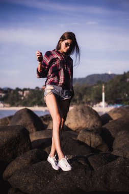 Pembe tişört ve güneş gözlüğü yakınındaki büyük taş rock plaj deniz okyanus sahilinde ince kadın portresi kapatın.