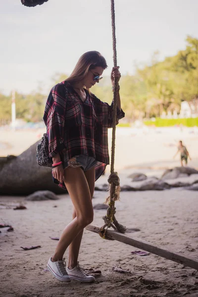 Menina bonito posando em uma praia. Ela segura uma corda e olha para longe. Foto perfeita para uma loja de moda — Fotografia de Stock