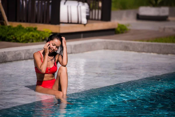 Mujer atractiva hablando en su teléfono móvil junto a la piscina — Foto de Stock