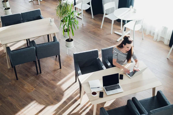 Bovenaanzicht van zakenvrouw aan tafel van medewerkers kantine, typen op een laptop. — Stockfoto