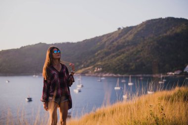Bir kız deniz kenarında uçurumun kenarında duruyor veya okyanus ve sun valley adlı arıyorum. Bir gün batımı veya gündoğumu dağın tepesinden kadının. Gezgin kızı görüyor güneş doğarken