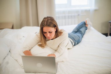 Heyecanla onun laptop ekranında gülümseyen sevimli genç bir kadın. O yatakta rahatlatıcı.