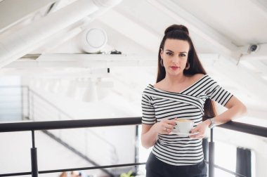 Güzel bir kadınla ana oda ayakta ve kameraya bakarak aromatik kahve.