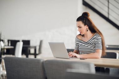 Genç kadın girişimci modern Restoran iç öğle yemeği sırasında dizüstü elektronik kitap okuma. Şık iş kadını rahat kafede otururken tablete sohbet.