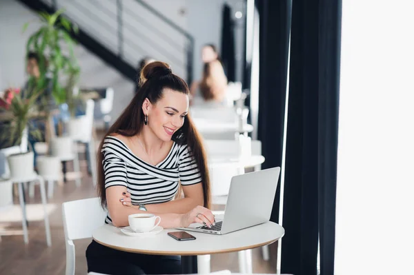 Bastante mujer con linda sonrisa hablando a través de Internet con su frind o pariente con una videollamada. Hermosa mujer feliz que trabaja en el ordenador portátil durante el descanso de café en el bar de la cafetería . — Foto de Stock