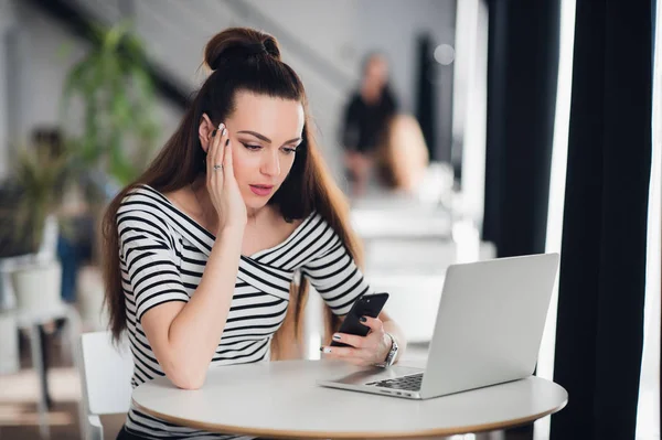 Mujer sorprendida sosteniendo y mirando tristemente al teléfono móvil, ella está decepcionada y desconcertada con el mensaje recibido . — Foto de Stock