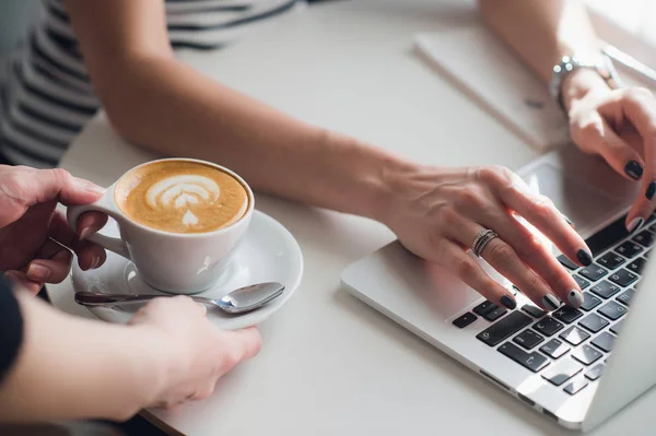Close-up foto van handen van een ober die een kopje cuppuccino om een vrouw te typen met een toetsenbord. — Stockfoto