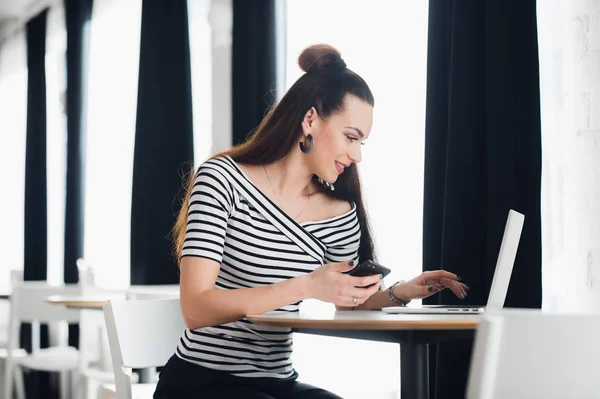 Portret van een vrouw te typen in een laptop tijdens de vergadering op de tabel in de buurt van venster en bedrijf telefoon. — Stockfoto
