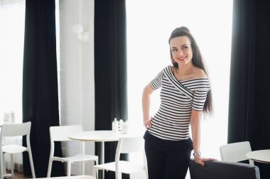 Neşeli kadın bir kafede bir pencereden bakıyor. Gülümseyen ve uzağa bakarak mutlu çekici Bayan.