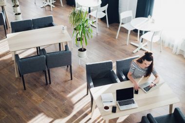 Orta yaşlı kadın yapma çağrısı ve kafede otururken dizüstü bilgisayar üzerinde çalışan.