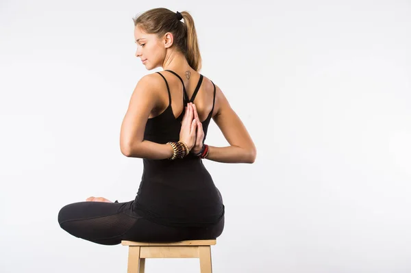 Känna sig avslappnad. Ung trevlig kvinna sitter i lotus pose på stol med slutna ögon och sätta hennes handflator ihop. — Stockfoto