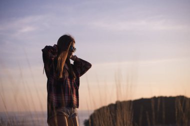 Bir kız deniz kenarında uçurumun kenarında duruyor veya okyanus ve sun valley adlı arıyorum. Bir gün batımı veya gündoğumu dağın tepesinden kadının. Gezgin kızı görüyor güneş doğarken