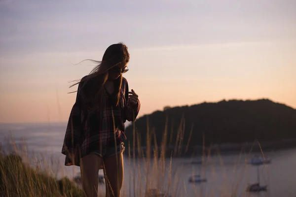 Hipster stylische Frau Reisende mit Blick auf ein Meer oder Ozean bei Sonnenuntergang — Stockfoto