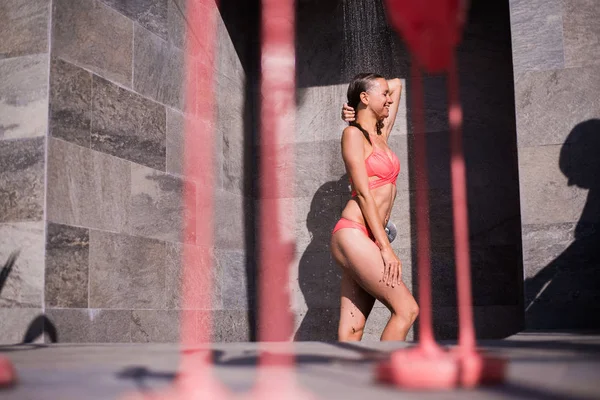 Attractive sexy woman under the shower outdoors near swimming pool at luxury hotel resort — Stockfoto