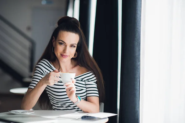 笑顔の女性が紅茶のカップでカフェでリラックス。コーヒーを飲むと、カメラを見て幸せのカジュアルな女性. — ストック写真