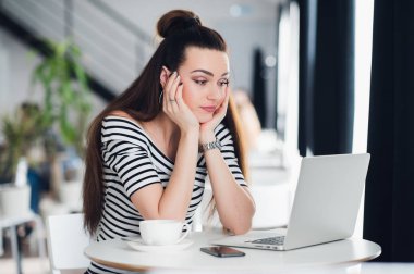 Onun öğle yemeği molası sırasında bir kafede oturan ve dizüstü bilgisayar ekranına bakarak hayal kırıklığına Bayan.