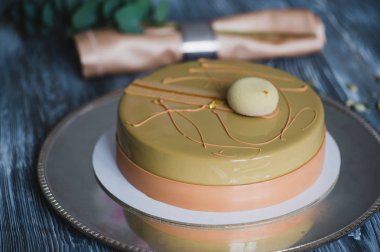 Badem dacquoise, ahududu confit, gevrek katmanla karamelize fındık ve ahududu tozu ile sarı puding kek fırından yeni çıkmış, ahşap masaya servis bağlı olarak bitter çikolata mousse