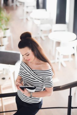 Çekici genç kadın ise bir kafede merdivenlerde ayakta ve aşağı bakıyor ona not defterinde yazma.