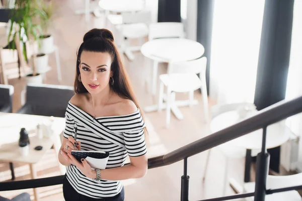 Hermosa mujer adulta con ropa casual está mirando a la cámara y sonriendo mientras sostiene un libro y toma notas en él . — Foto de Stock